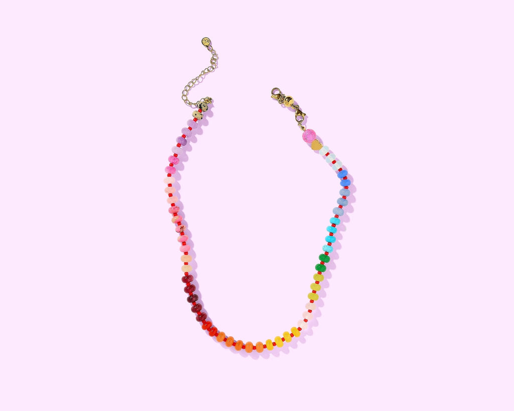 Colorful beaded necklace on a light pink background