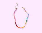 Colorful beaded necklace on a light pink background
