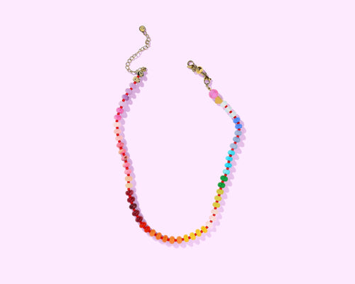 Colorful beaded necklace on a light pink background